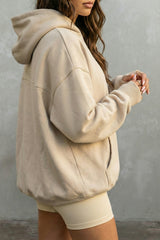 Person wearing a beige hoodie and white shorts against a gray background